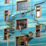 Kunstvoll verlegte Regenrohre an wasserblauer Fassage