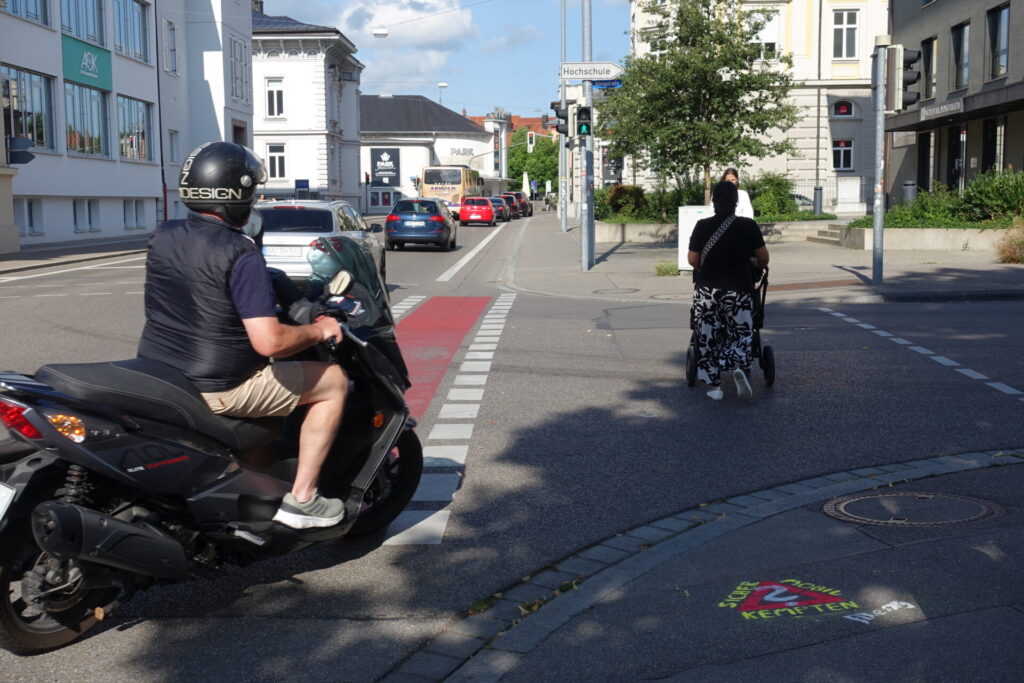 Graffito "Sicher mobil in Kempten?" mit rechtsabbiegendem Kraftradfahrer