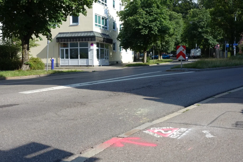 Graffito "SIcher mobil in Kempten?" auf Gehweg, mit Pfeil in Richtung Mozartstraße