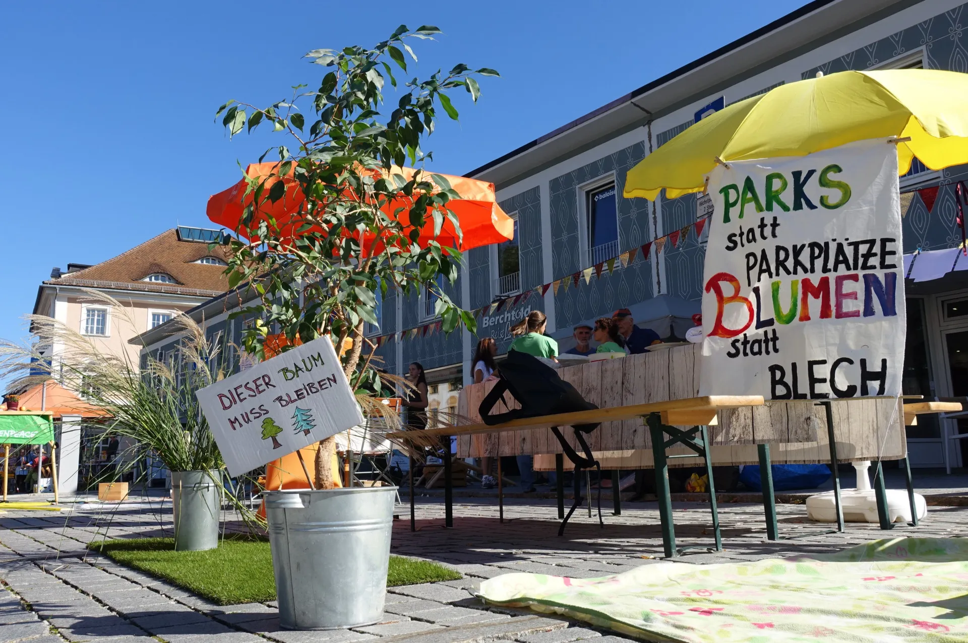 Park(ing) Day am Residenzplatz Kempten: Banner "Parks statt Parkplätze, Blumen statt Blech", Topfpflanze